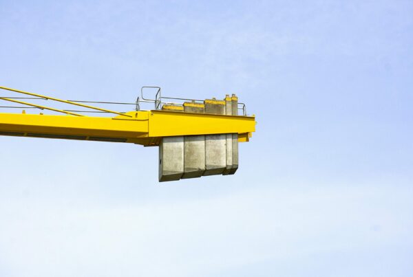 Industrial rigging crew performing heavy equipment lifting and crane operations in manufacturing facility