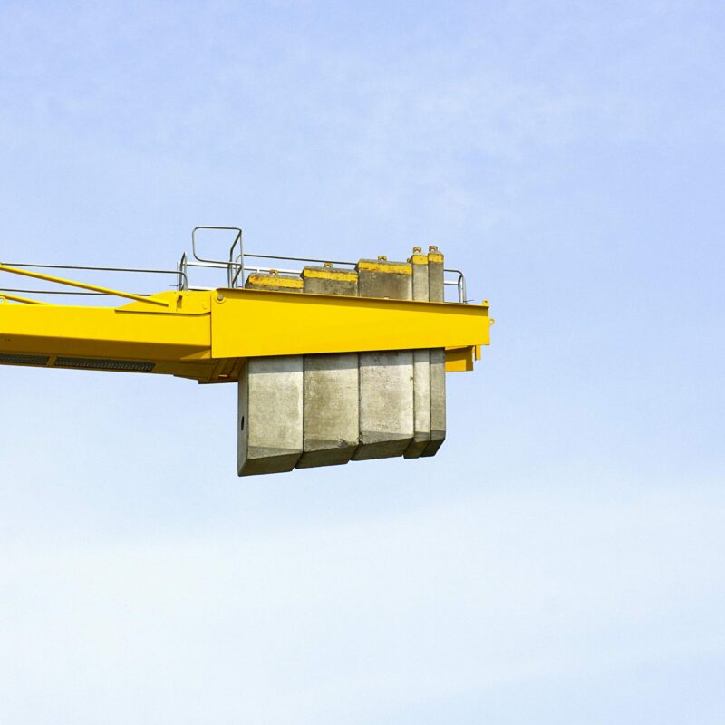 Industrial rigging crew performing heavy equipment lifting and crane operations in manufacturing facility