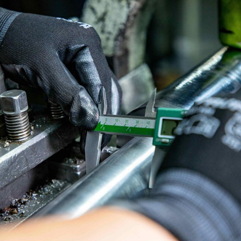 Millwright technician using a digital caliper to measure shaft tolerance during emergency equipment repair in an Atlanta manufacturing facility