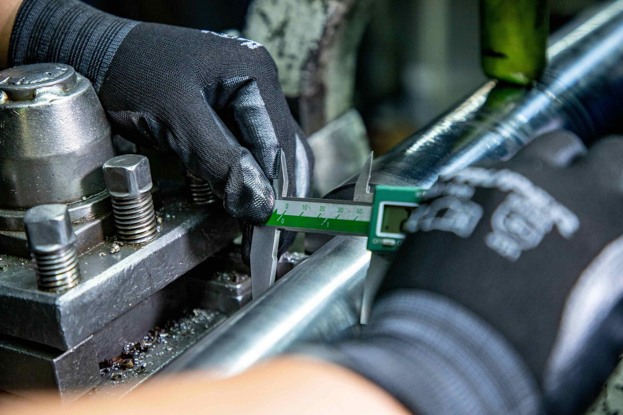 Millwright technician using a digital caliper to measure shaft tolerance during emergency equipment repair in an Atlanta manufacturing facility